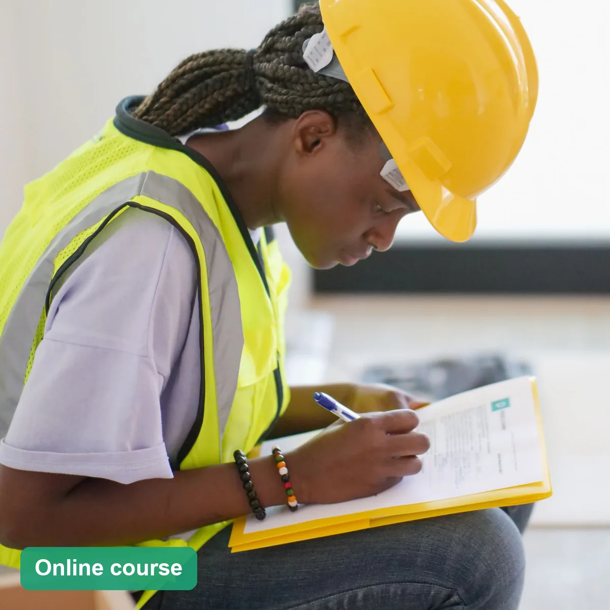Safety officer in hi-vis and a hard hat writing up an incident report (online course)