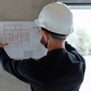 Site supervisor in a hard hat reviewing a building plan