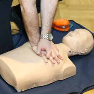 Trainee practising CPR chest compressions on a training manikin