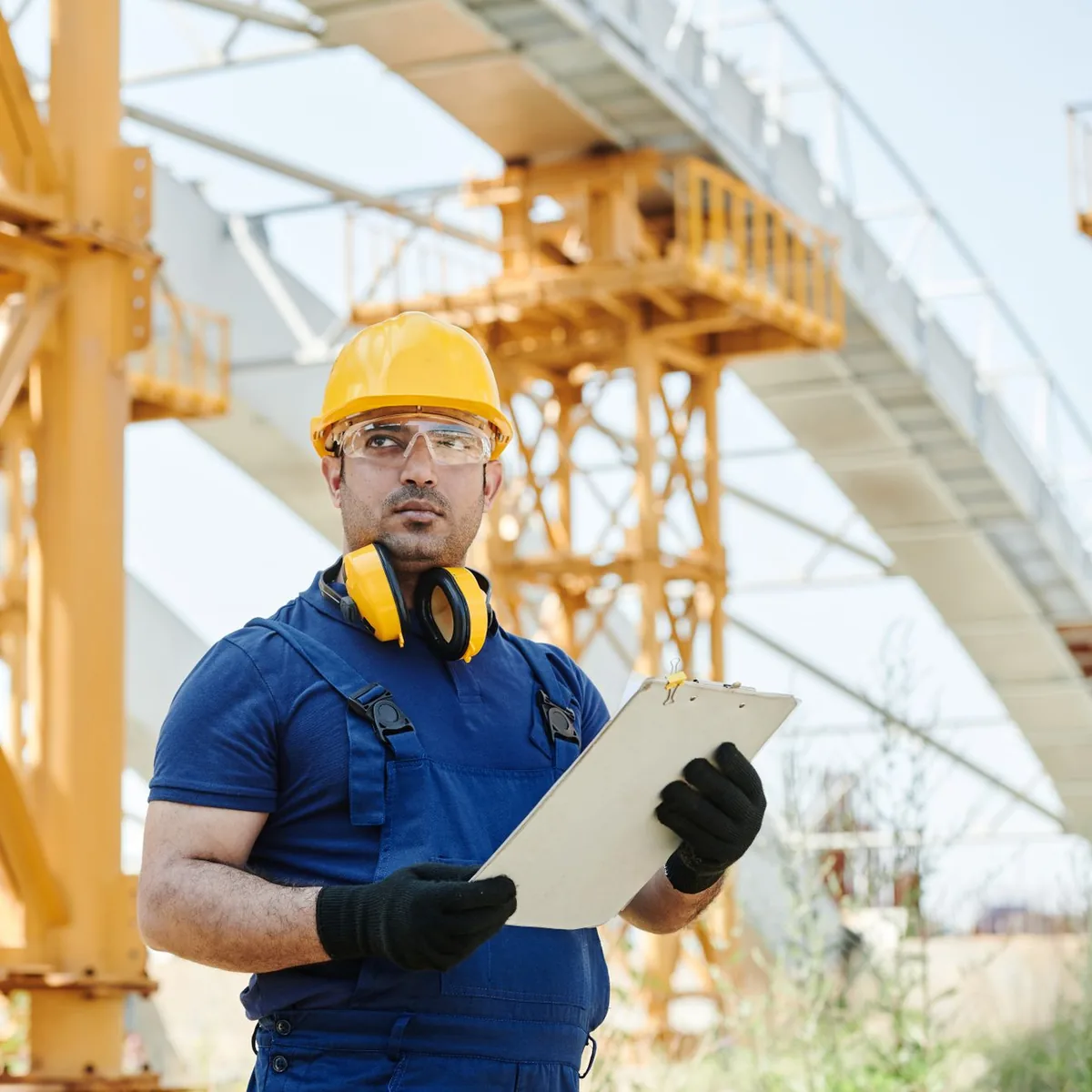 Health and safety representative in a hard hat doing a site inspection with a checklist